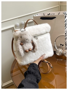 Détail d'un sac seau en peluche blanche avec un charme de lapin et une bandoulière marron
