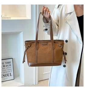 Close-up of brown suede tote bag with smooth leather stitching and drawstring detail