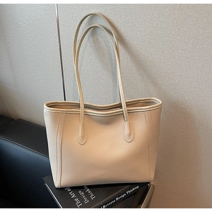 Close-up of beige pebble leather texture and long shoulder strap on a commute tote bag