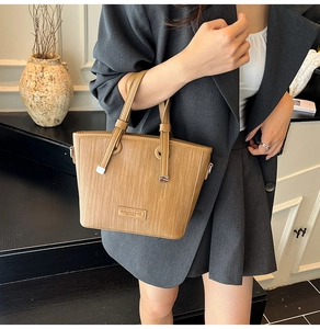 Detail of vintage brown woven tote bag featuring leather handles and metal hardware accents