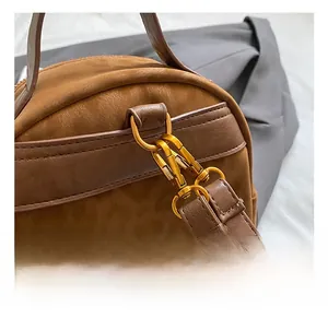 Close-up of golden metal hook and brown suede texture on a vintage canvas backpack