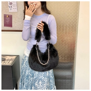 Detail of plush black faux fur handbag with elegant pearl and metal chain decoration
