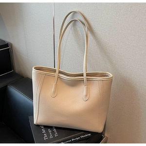 Detailed close-up of beige tote bag showing high-quality lychee grain leather texture