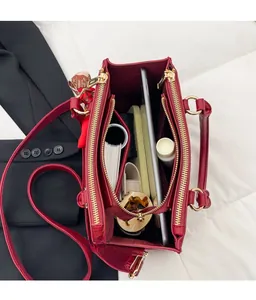 Internal view of red litchi leather tote showing multiple storage compartments and golden zippers