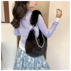 Detailed side view of black faux fur shoulder bag with gold chain and plush texture