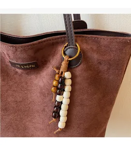 Detail of brown suede tote bag with leather handles and bohemian beaded tassel charm