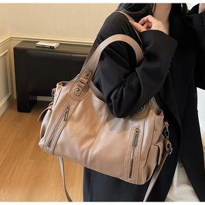 Close-up of a large beige tote bag featuring vertical zippers and premium leather texture