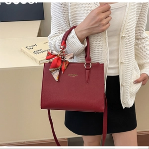 Close-up of red lychee grain leather handbag with printed silk scarf and gold logo