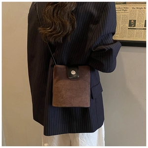 Detail shot of vintage brown suede crossbody bucket bag with black leather flap and silver buckle