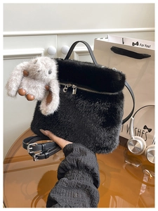 Détail du sac seau en fausse fourrure noire avec breloque lapin et bandoulière