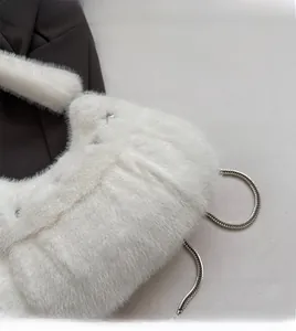 Close-up of white faux fur handbag with soft plush texture and silver metal chain strap