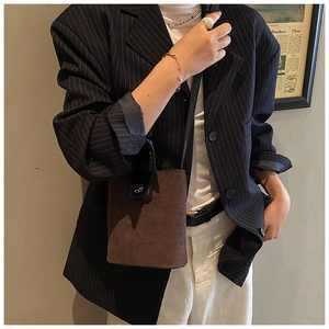 Close-up of dark brown suede bucket bag with black strap on casual stylish outfit