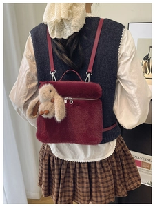 Détail du sac seau bordeaux en fausse fourrure avec pendentif lapin sur un modèle