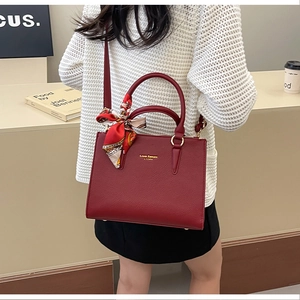 Detail of burgundy textured leather tote bag with elegant floral scarf on handle