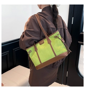 Model wearing a large green suede tote bag with brown leather trim and tassels