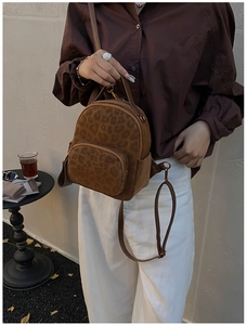 Detail view of mini leopard print backpack worn as a stylish crossbody bag in a cafe