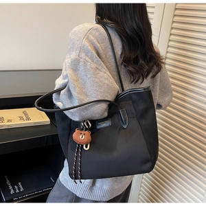 Nahaufnahme der schwarzen Nylon-Tragetasche mit süßem braunem Plüschbären-Anhänger und Logo