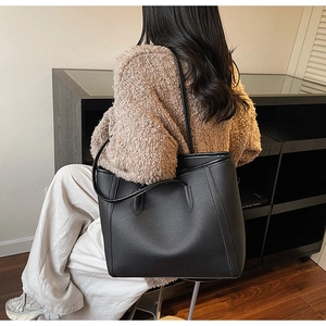 Close-up of black leather tote bag featuring natural lychee texture and fine stitching