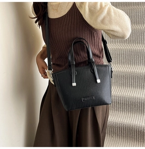 Detail of black woven texture leather bucket bag with silver hardware and shoulder strap