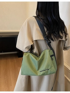Green plaid canvas crossbody bag with adjustable wide strap shown on a female model
