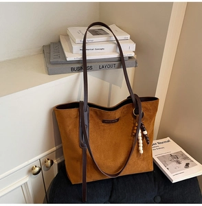 Detail of caramel suede tote bag featuring slim straps and wooden bead accessory decor