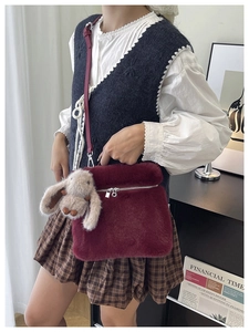 Détail d'un sac seau en peluche bordeaux avec un charmant porte-clé lapin gris suspendu