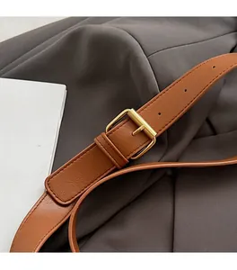 Detail of premium brown leather strap with brushed golden metal buckle on a retro bag