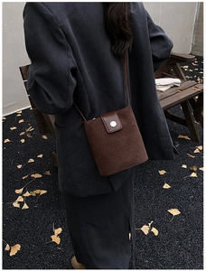 Detail of dark brown suede bucket bag with silver round buckle in an autumn setting