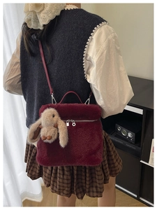 Gros plan du sac seau en peluche bordeaux avec un charme de lapin et fermeture argentée