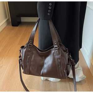 Detail of dark brown lychee grain leather tote bag with silver zippers and strap