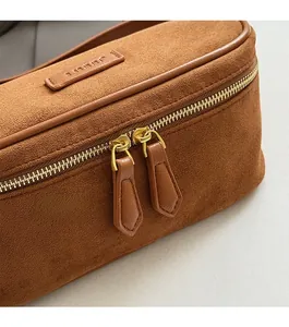 Close-up of brown suede Boston bag showing neat stitching and gold-tone zippers