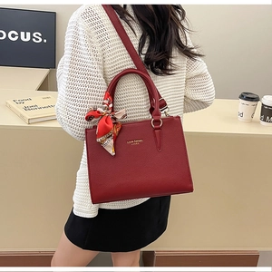 Detail of burgundy textured tote bag with silk scarf and adjustable strap shown on model