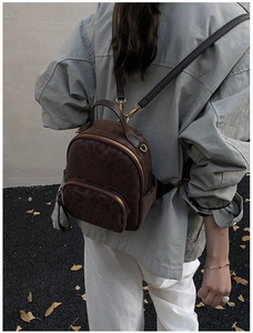 Outdoor shot showing back view of leopard print mini backpack with gold metal zippers