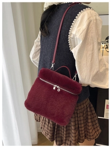 Détail du sac seau en peluche bordeaux montrant la texture et le zip argenté