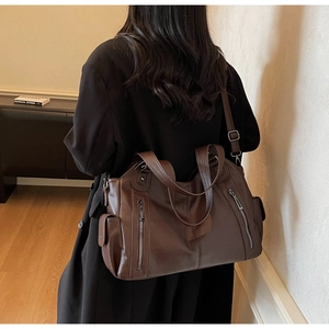Rear view of a model wearing a brown pebbled leather tote bag with multiple zip pockets