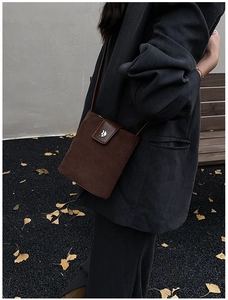 Side view of dark coffee suede bucket bag with silver buckle worn by a model