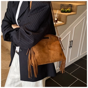Detail of brown faux suede crossbody bag featuring retro fringe and zipper closure
