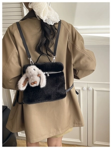 Vue de dos d'un sac seau en peluche noire avec une poupée lapin blanc et bandoulière