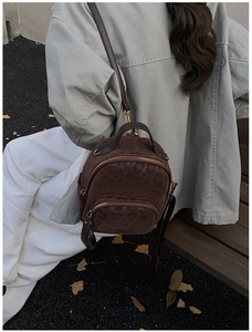 Detail of dark brown leopard print backpack with soft suede texture and dual zippers