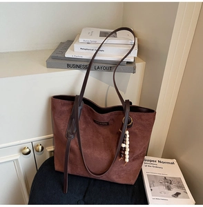 Close-up of brown suede tote bag with decorative wooden beads and metal ring detail