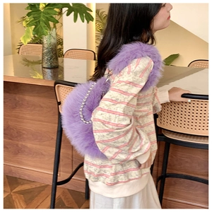 Close-up of purple fuzzy crescent bag with silver beaded strap worn by a model
