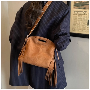 Close-up of brown suede crossbody bag with long fringe tassels and cutout handle