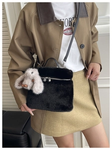 Détail du sac seau en peluche noire avec breloque lapin et poche zippée à l'avant