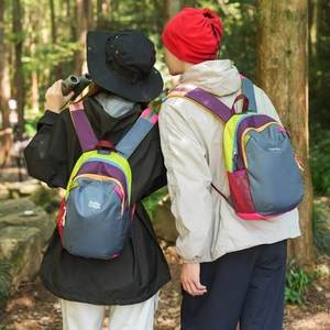 Close-up of lightweight color-block backpacks with side mesh pockets in a forest setting