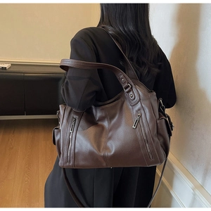 Detail of dark brown leather tote with litchi texture and functional side pockets