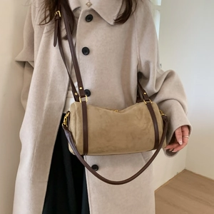 Détail du sac polochon en daim avec sangles en cuir contrastées et finitions dorées