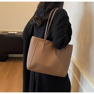 Close-up of khaki pebbled leather tote bag with fine stitching and slim shoulder straps
