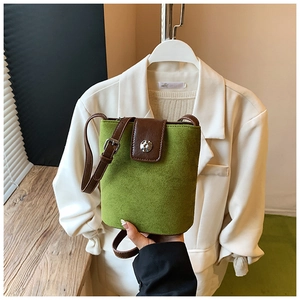 Detail of green faux suede bucket bag with brown leather trim and silver metal magnetic clasp