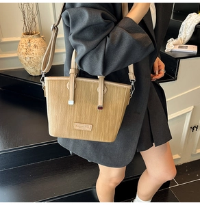 Close-up of khaki woven bucket bag texture with leather handle and adjustable strap