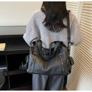 Detailed view of black litchi grain leather tote with multiple zipper pockets on strap